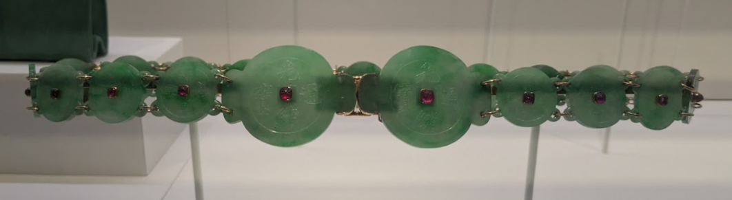 Belt made up of a series of small green jade discs with a central ruby. The clasp is made up of two larger discs. 