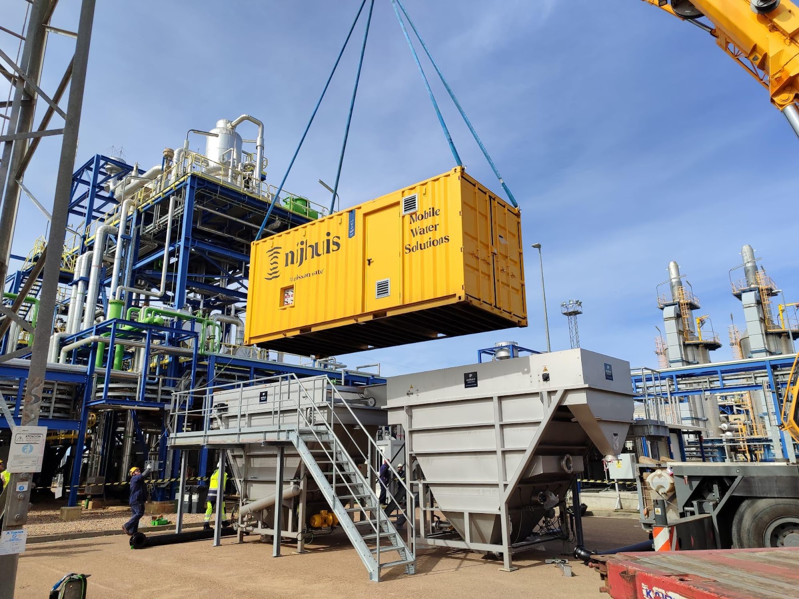 A yellow container being lifted by a crane

Description automatically generated