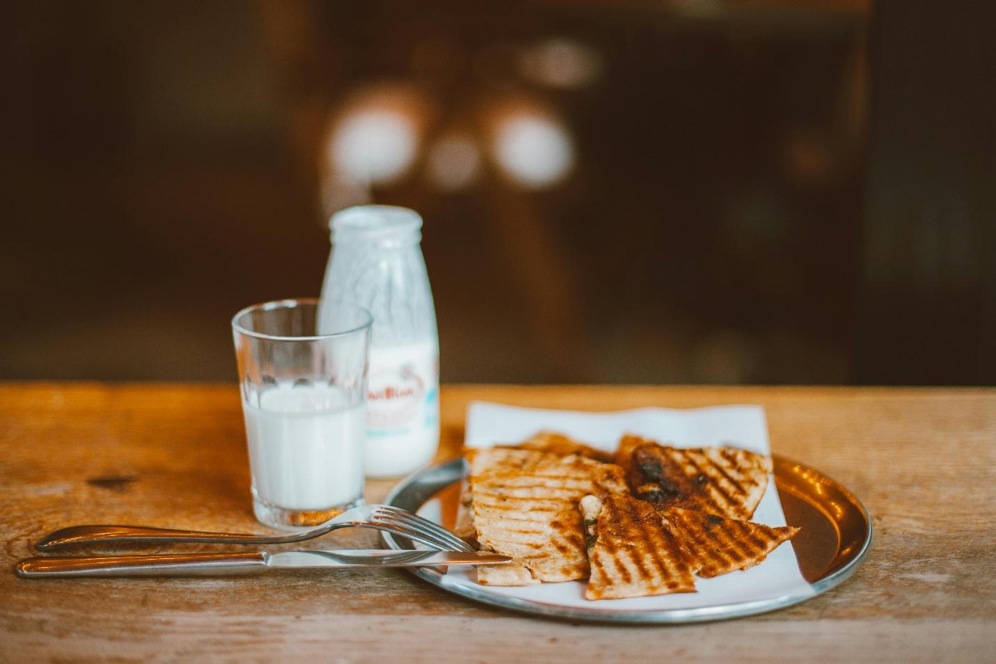 A plate of food and milk on a table

Description automatically generated