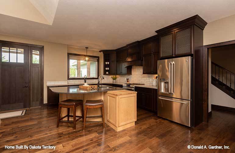 Kitchen with dark wood cabinetry, stainless steel appliances, and a large curved island with a snack bar.