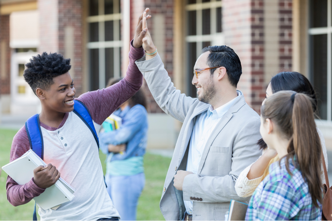 High school student high-fiving a teacher after class