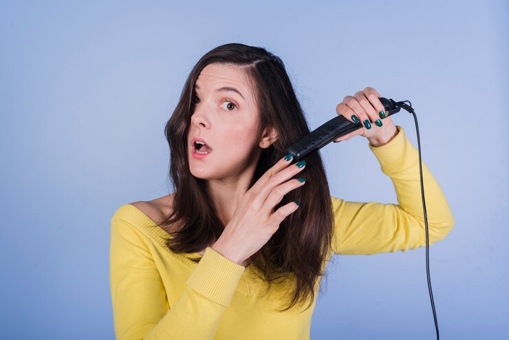 Brunnete girl with shocked expression styling hair with straightener