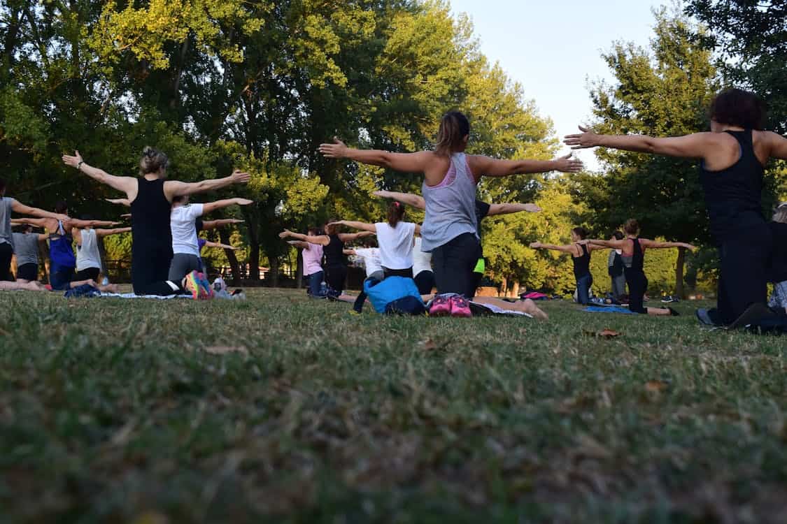 Mulheres ao ar livre em um gramado praticando hatha yoga, ideal para iniciantes.
