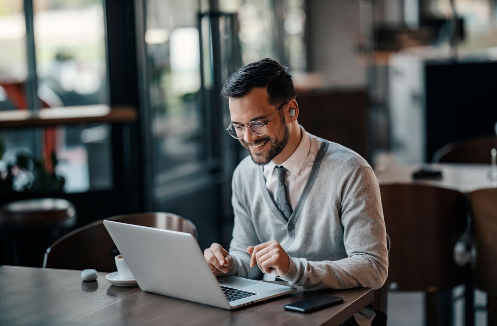 A person smiling while wearing digital lenses as they work on their laptop.