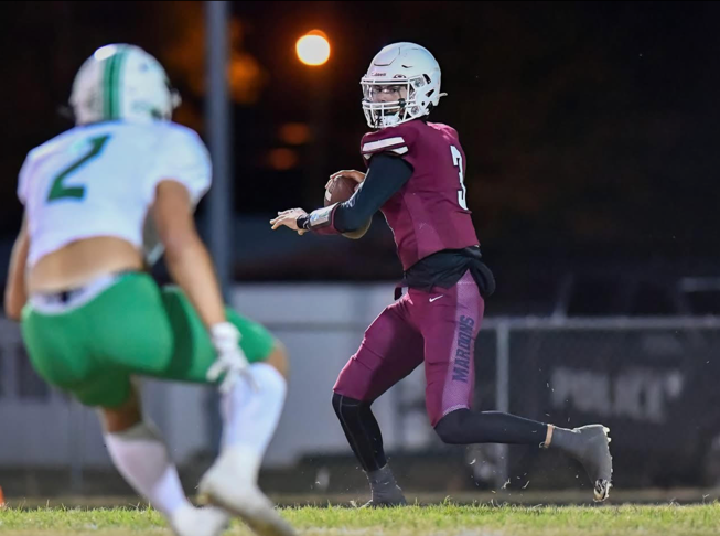 A football player in a helmet running with a football

Description automatically generated