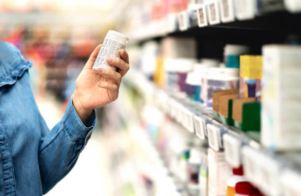 A health-conscious individual carefully examines the label of a multivitamin bottle, checking ingredients and nutritional value before making a choice.