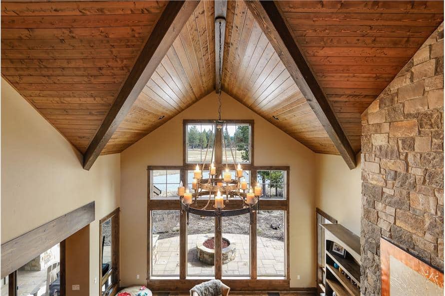 A vaulted ceiling clad in wood planks and mounted with a two-tier chandelier crowns the great room.