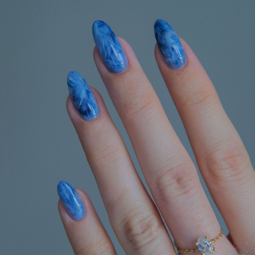 Close up of hands with blue winter nails having Smokey marble