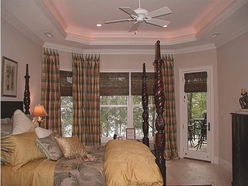 The primary bedroom features a tray ceiling, a four-poster bed, and a bayed sitting area.
