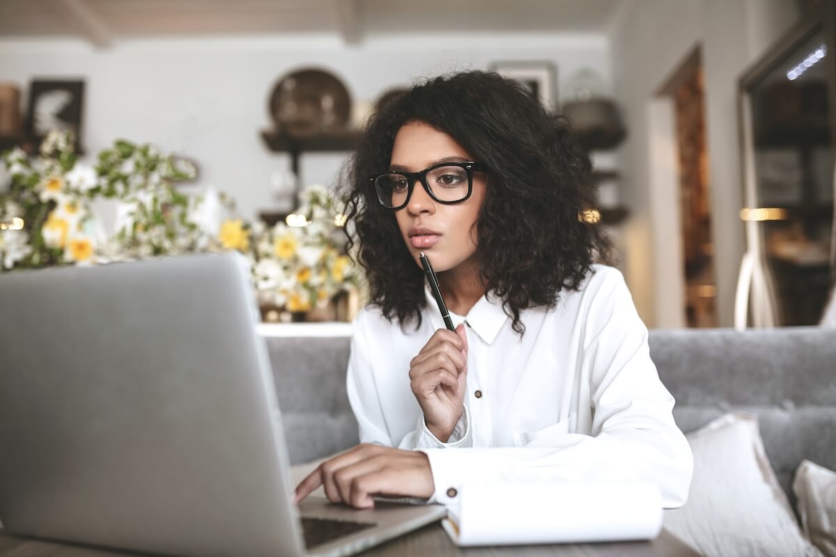 Clinical documentation software: woman using her laptop while holding a pen