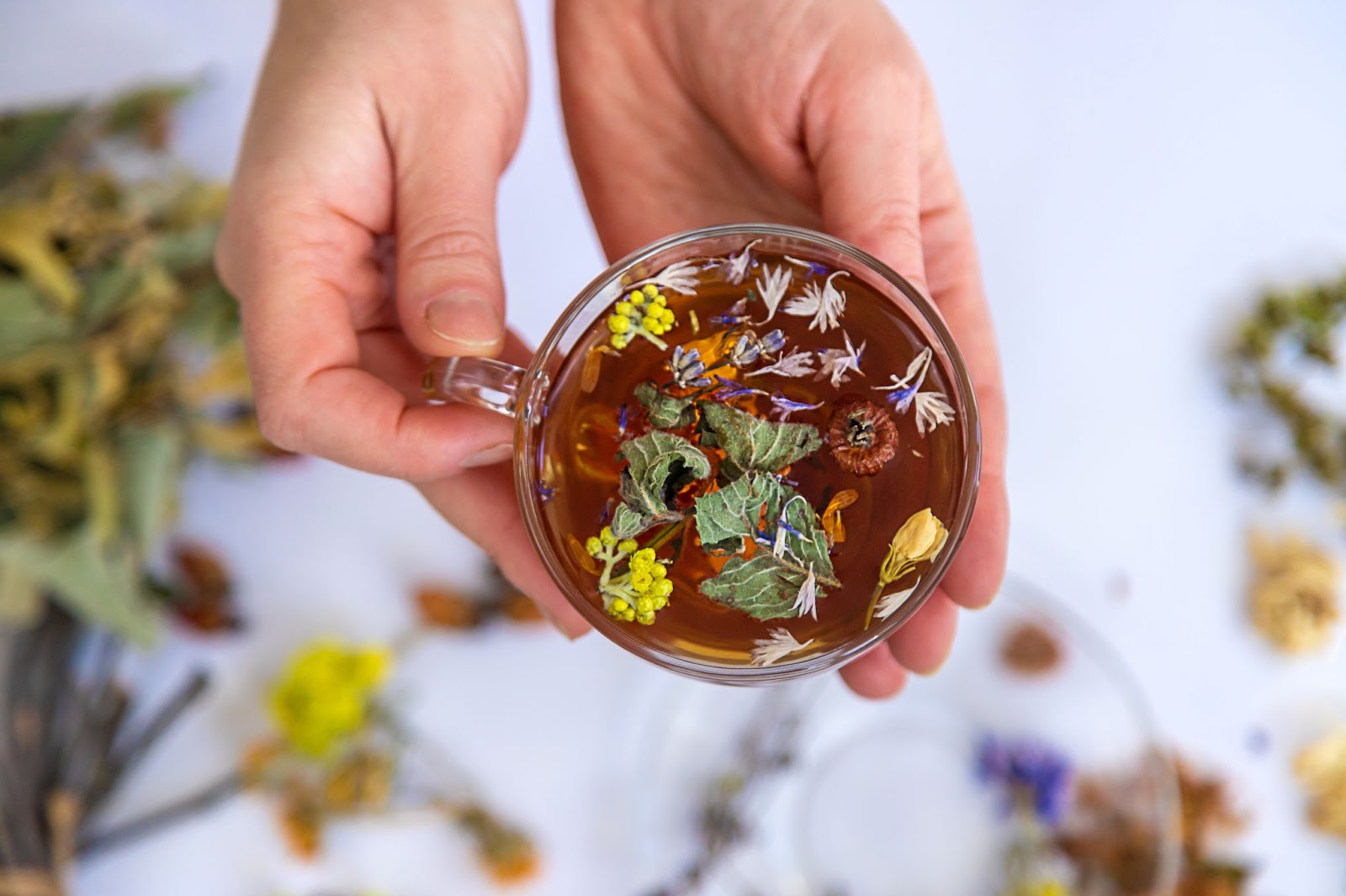 Person holding a glass cup of herbal tea. 