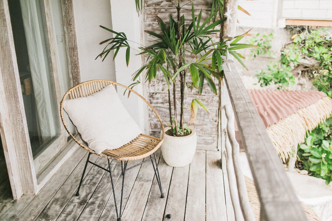 Potted plant and a single chair arranged on a wooden balcony, creating a simple, inviting outdoor seating area.