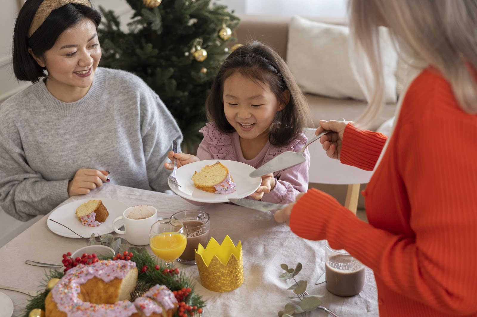 Seorang wanita dan dua anak sedang menikmati sarapan bersama di meja makan yang ceria.