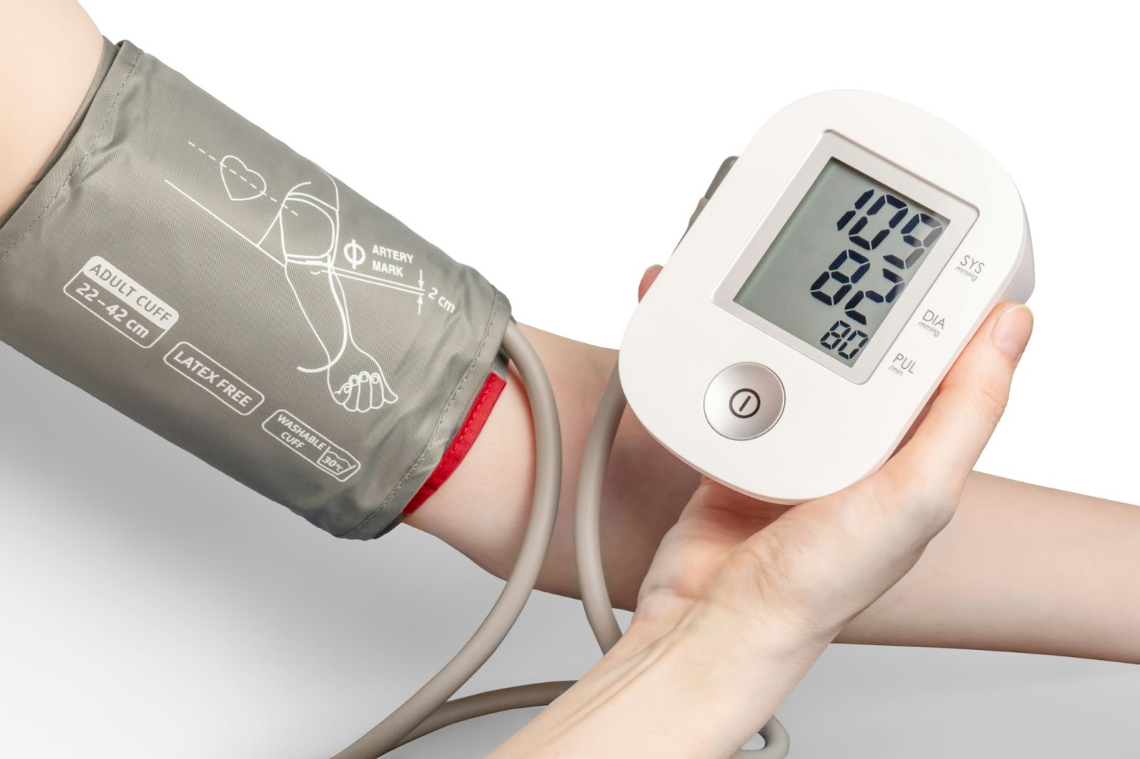 Close-up of an automatic blood pressure monitor showing a reading on a person’s arm