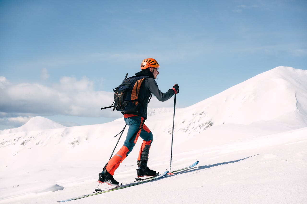 Man with skis and gloves climbing up a hill
