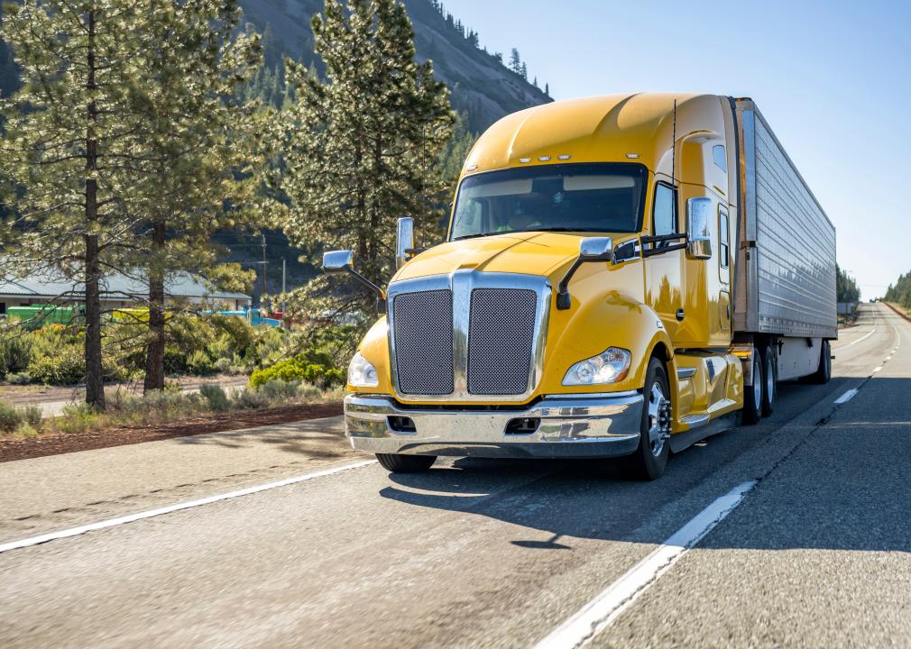 Classic long haul yellow semitruck on road.