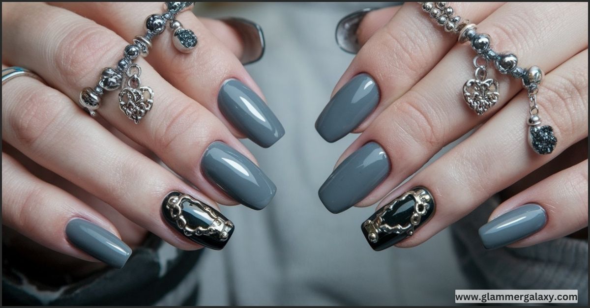 Gray manicured nails with silver jewelry on fingers against a gray background.