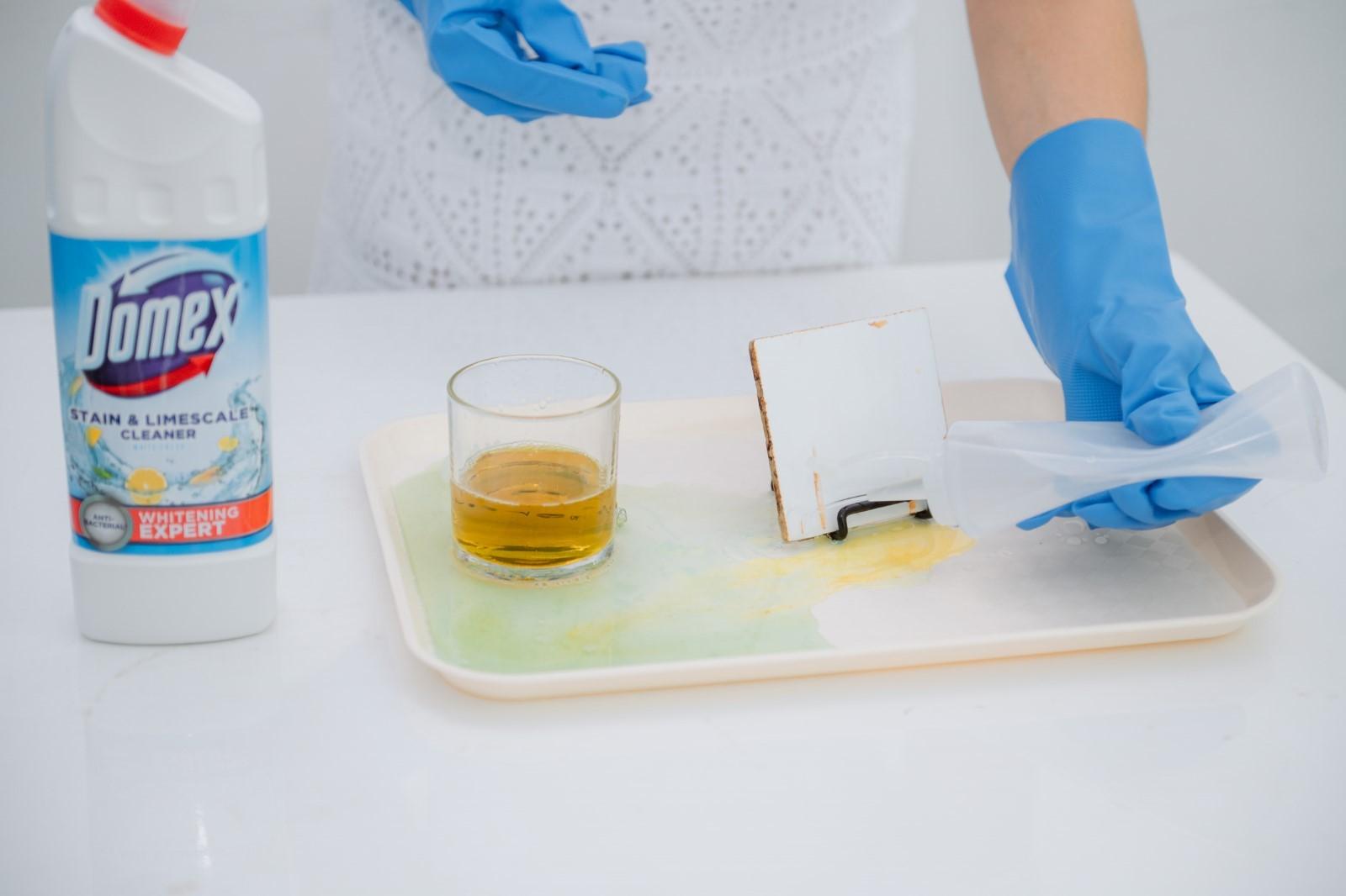 A person wearing blue gloves cleaning a tray with a glass of liquid

Description automatically generated