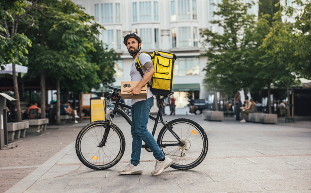 Repartidor en bicicleta sosteniendo un paquete ecológico