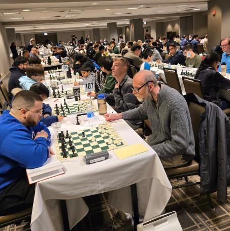 A group of people sitting at a table playing chessDescription automatically generated