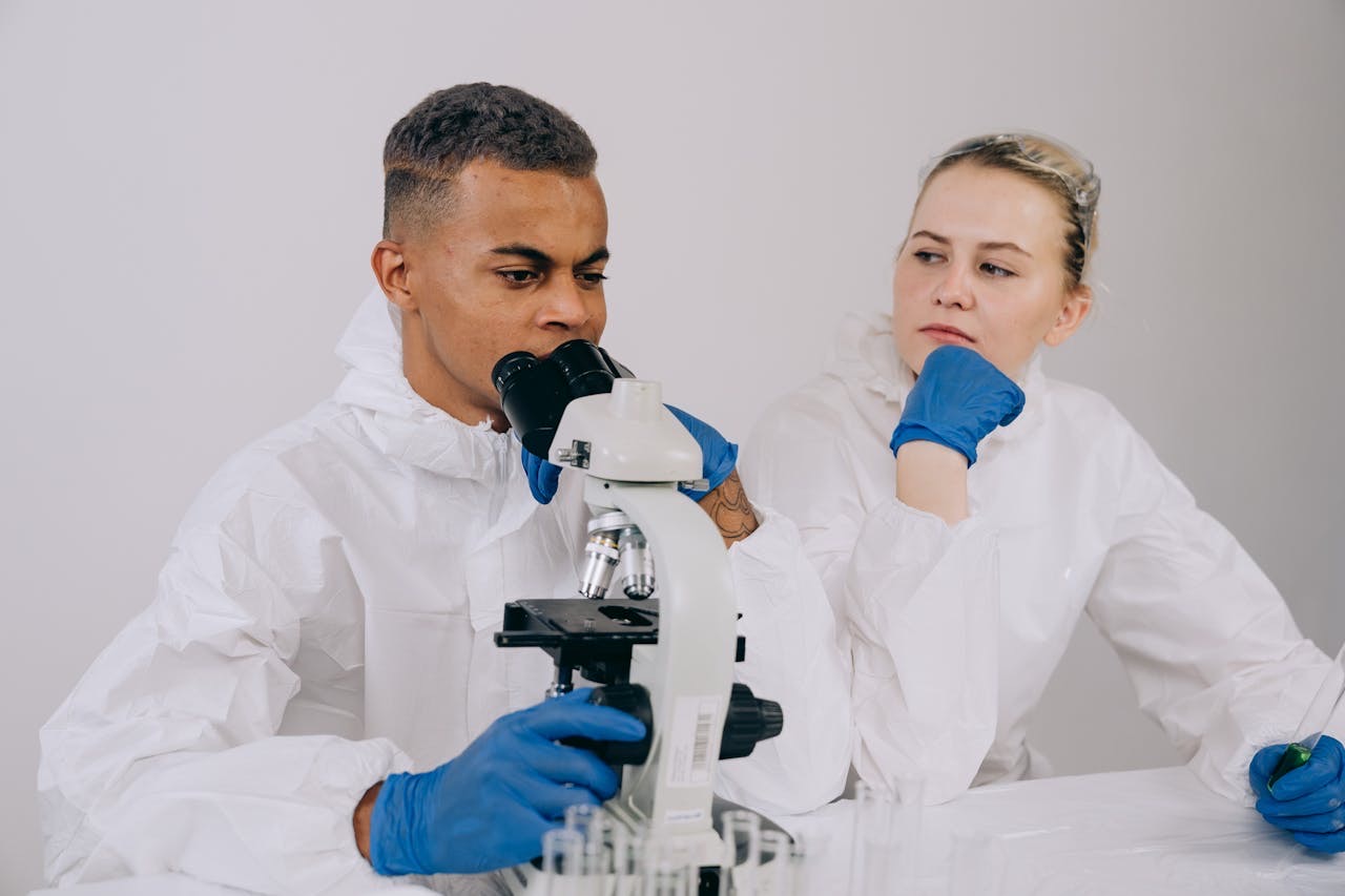 Tests being done in a lab by a man and woman, wearing white coats and blue gloves // Healthier Baby Today