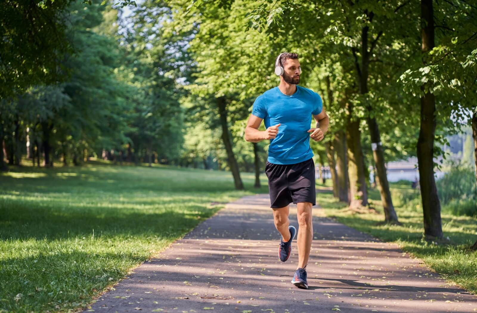 An athletic person jogs through a sunny park with proper form.