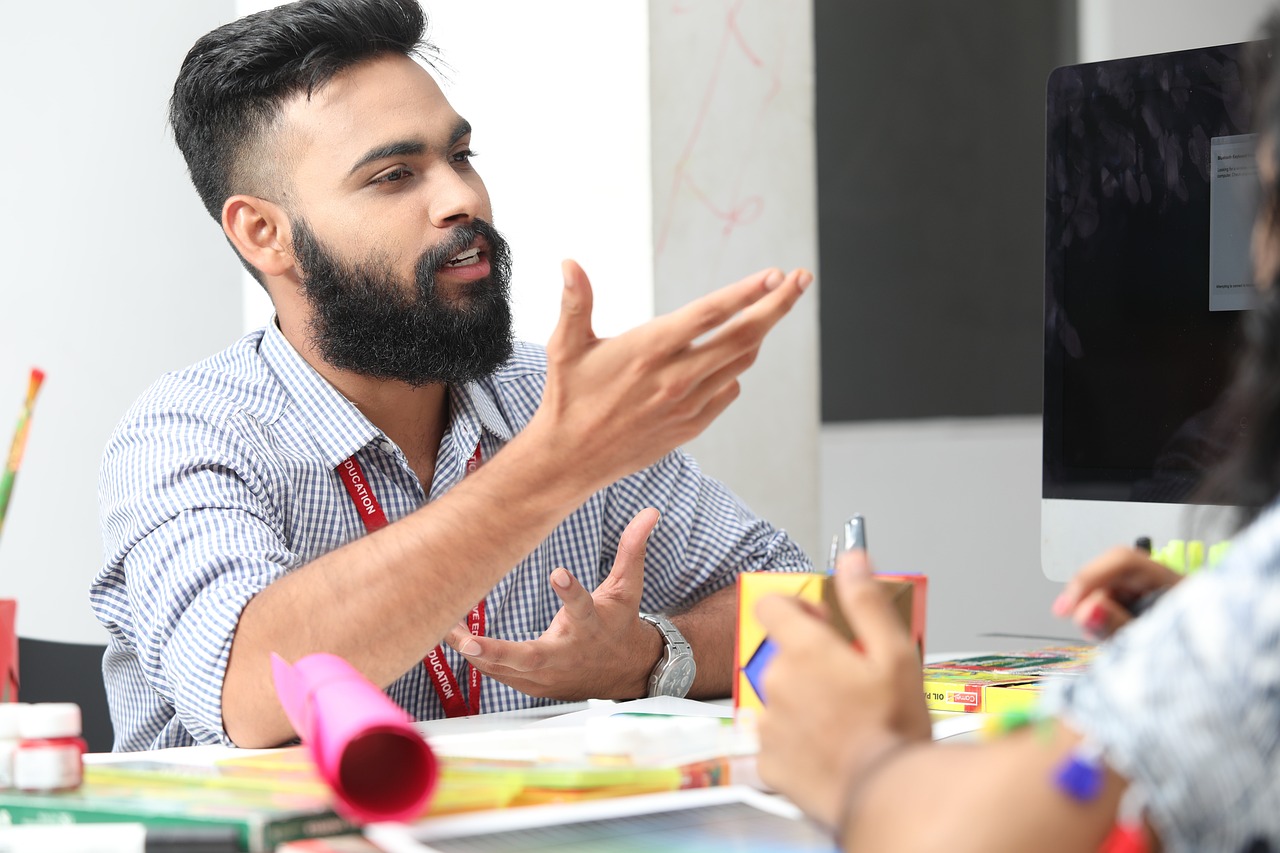 A person sitting at a table seemingly talking to other people. White background. 