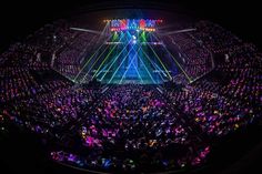 This contain an aerial view of a concert venue at night with colorful lights on the stage and in the audience