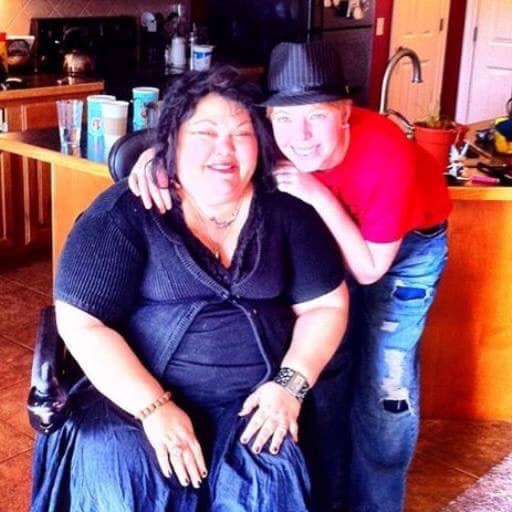 Wendy Lovedge sits in a wheelchair and poses for a picture with her wife.