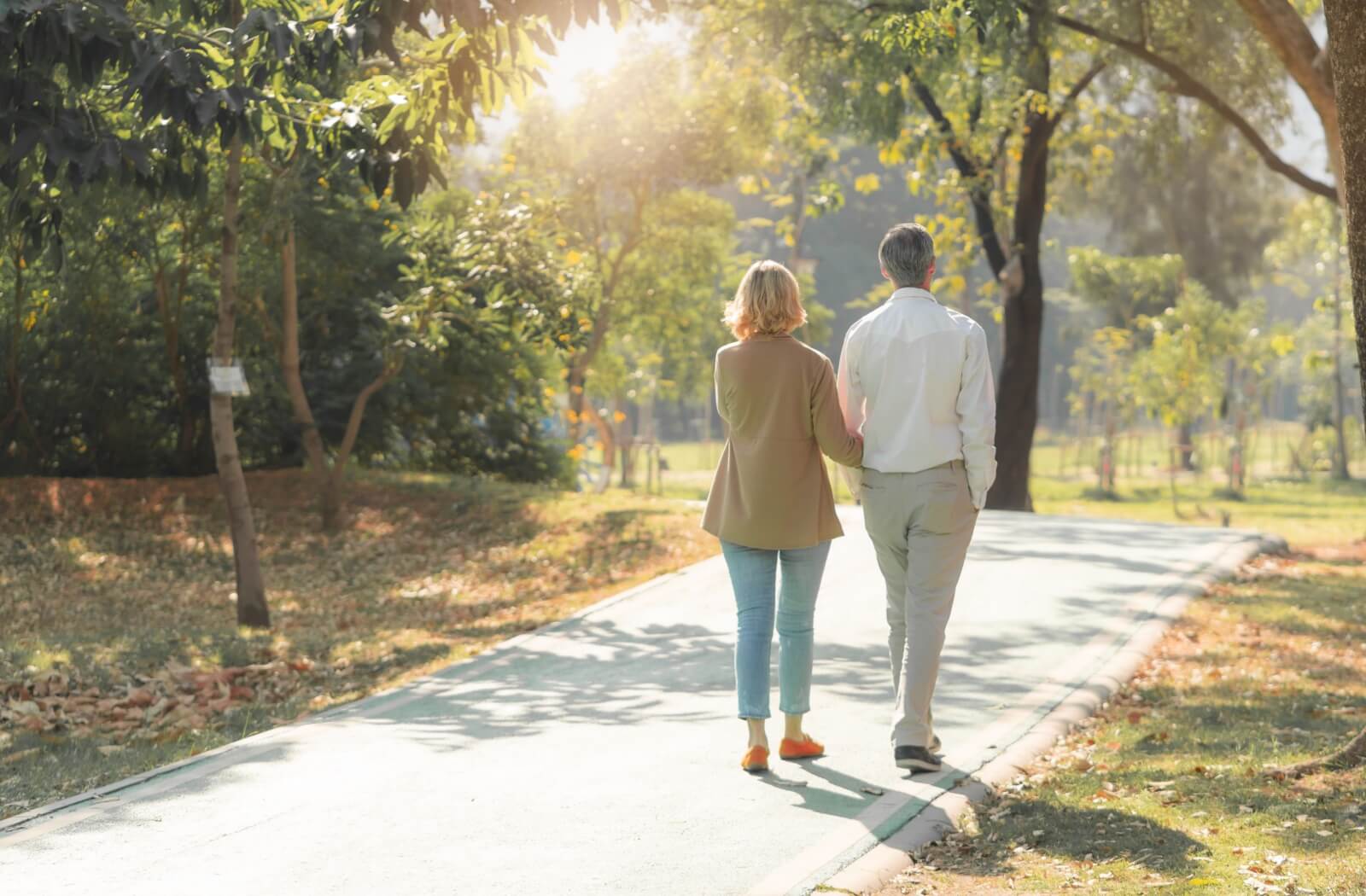 Older couple walking through a park on a sunny day to stimulate their appetite.