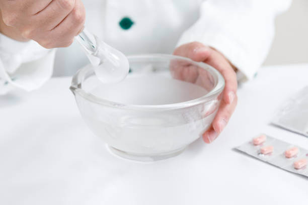 A pharmacist carefully preparing a custom medication in a lab.