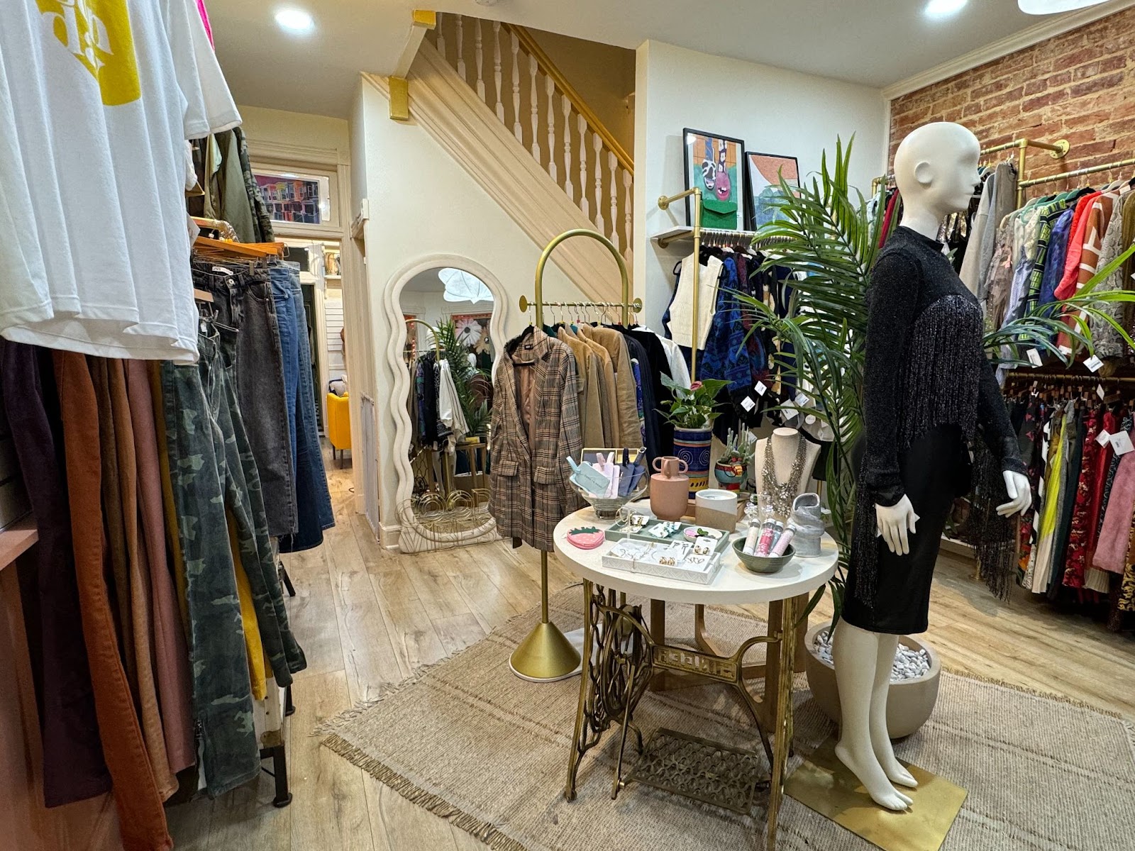 Racks of clothing and a table of accessories inside of a consignment shop.