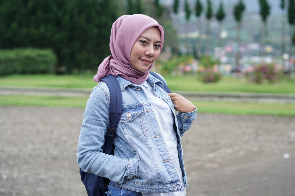 Wanita dengan baju denim dan jilbab dusty pink.