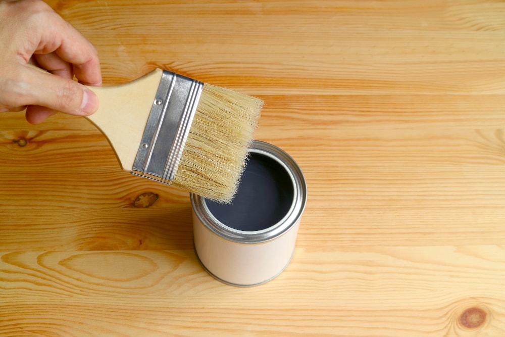 Perbandingan Cat Kayu dengan Thinner (https://www.freepik.com/premium-photo/hand-holding-paintbrush-reaching-opened-paint-can-wooden-plank-with-free-space-design_5014227.htm#fromView=search&page=1&position=5&uuid=e83e91b1-978e-43ff-81b0-71cba4d61532)