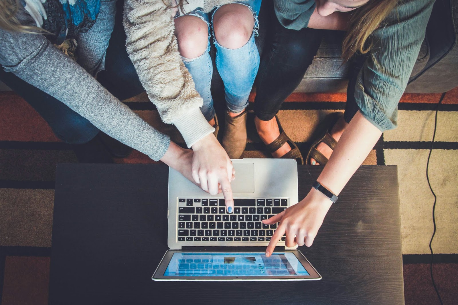 Three women pointing at a laptop while sitting next to each other