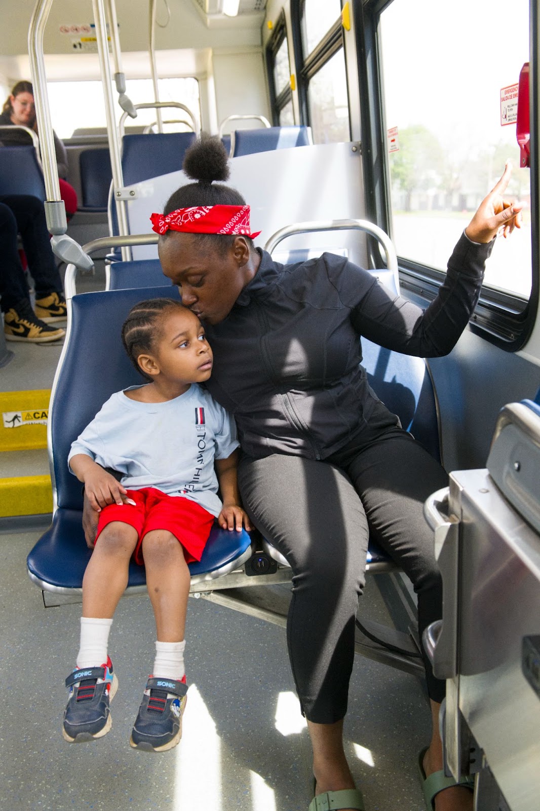 A mother kissing her child on the head on the bus A mother kissing her child on the head on the bus
