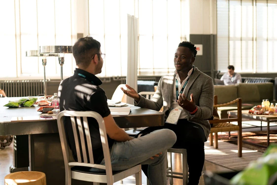 two men talking at a table; optimism