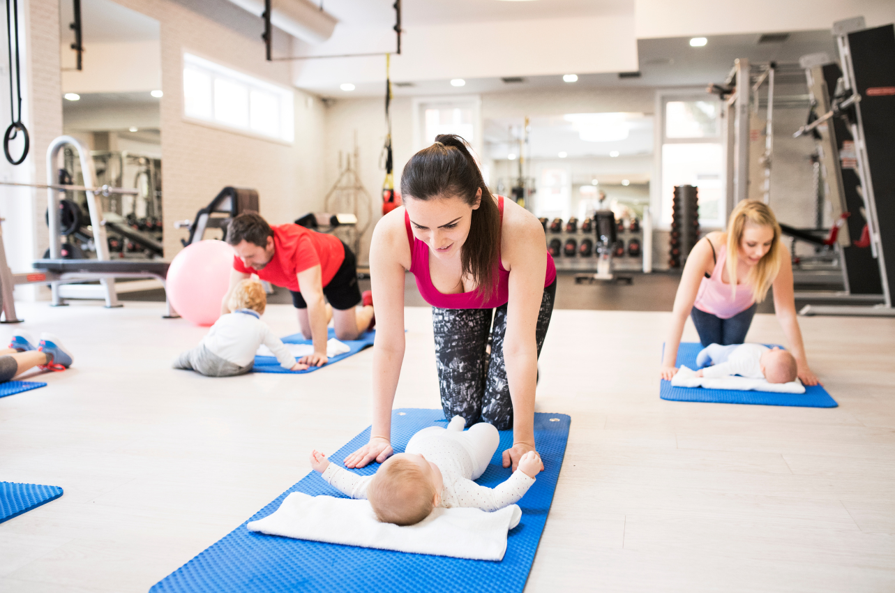 Mothers and babies in a gym class trying activities / Healthier Baby Today