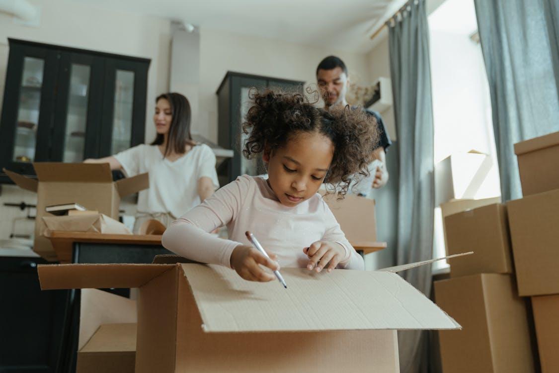 Free A family joyfully unpacking boxes in their new kitchen, marking a fresh start. Stock Photo