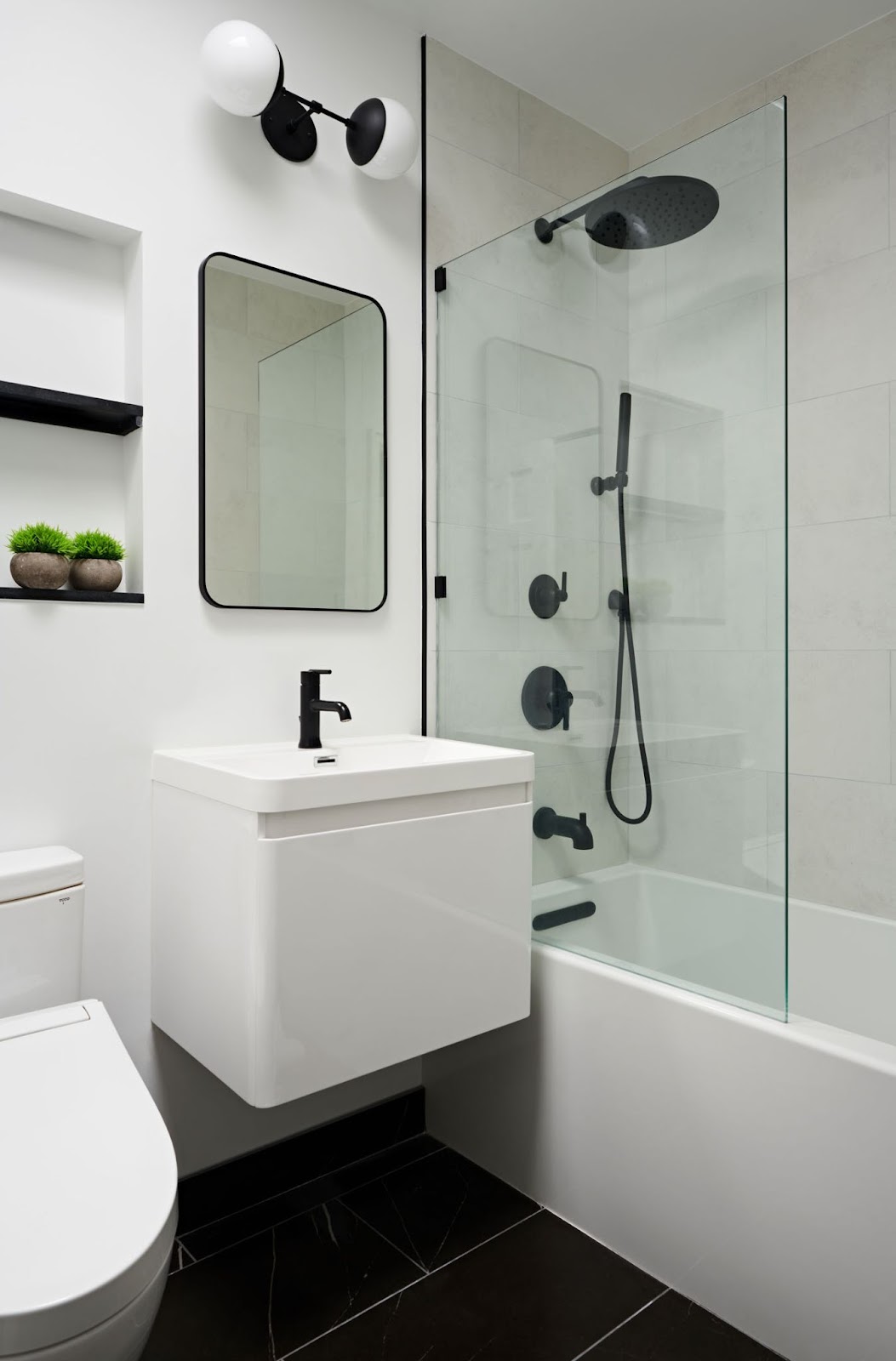 Small New York bathroom with a white floating vanity, matte black fixtures, and black large format tile flooring