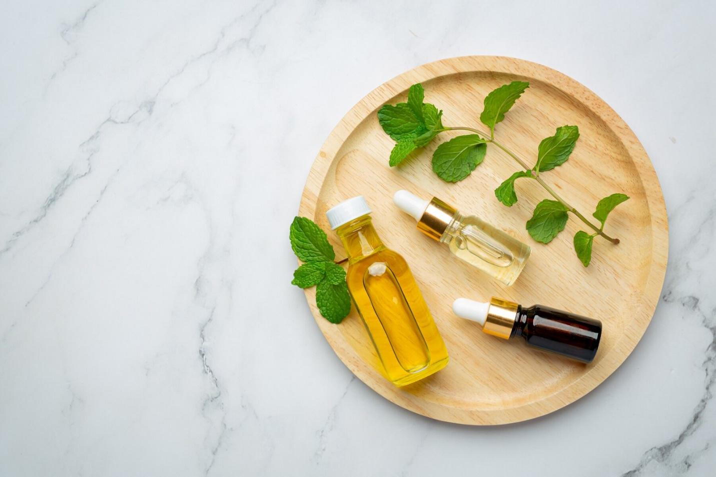 A group of bottles of oil on a wooden plateDescription automatically generated
