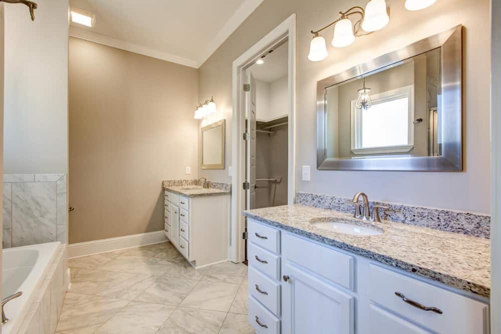 Primary bathroom with his and her sink vanities flanking the walk-in closet.