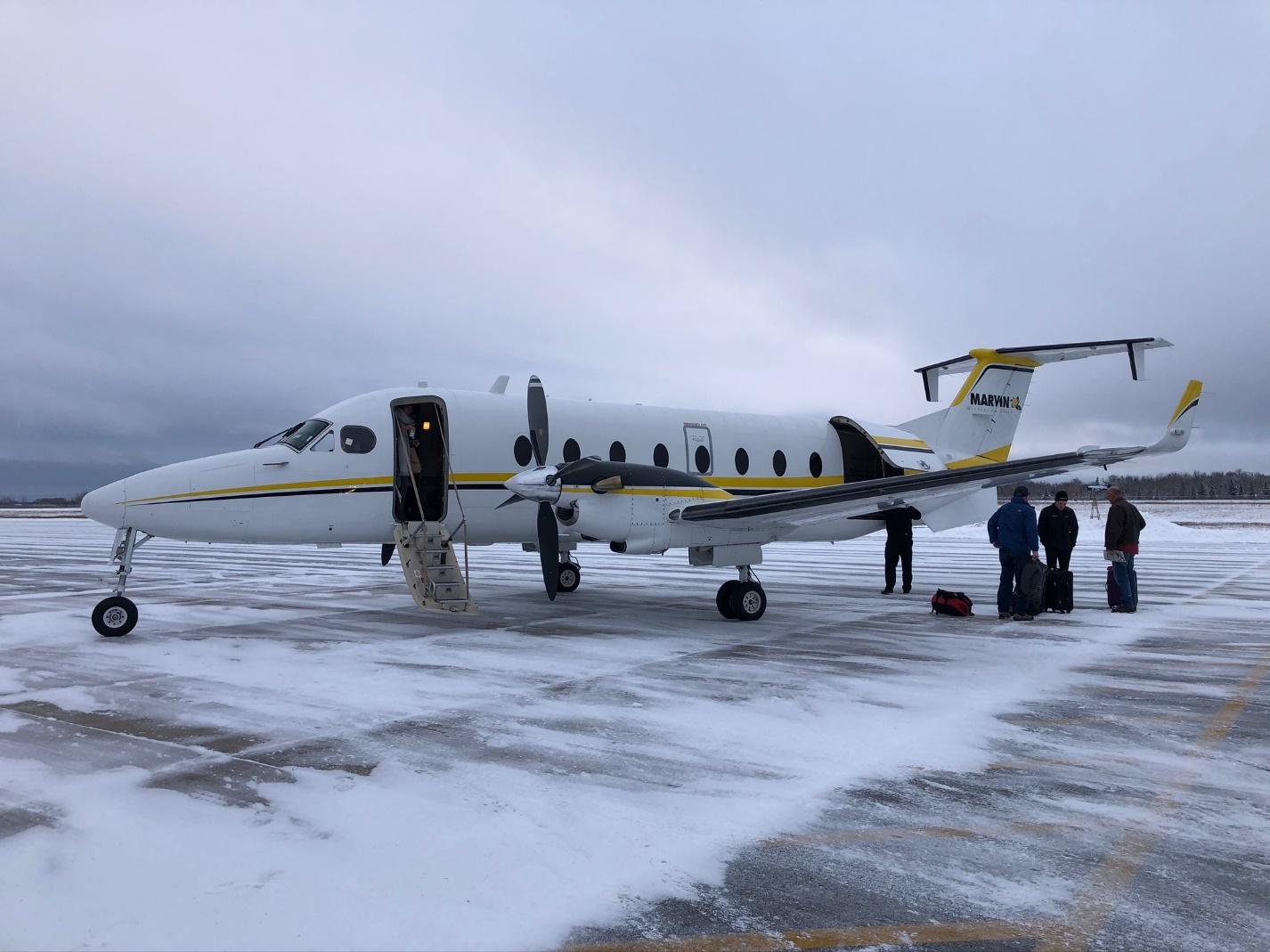 A group of people standing next to a plane

Description automatically generated