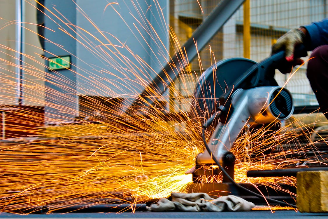 Worker using power tool with flying sparks, illustrating risk management in construction projects.
