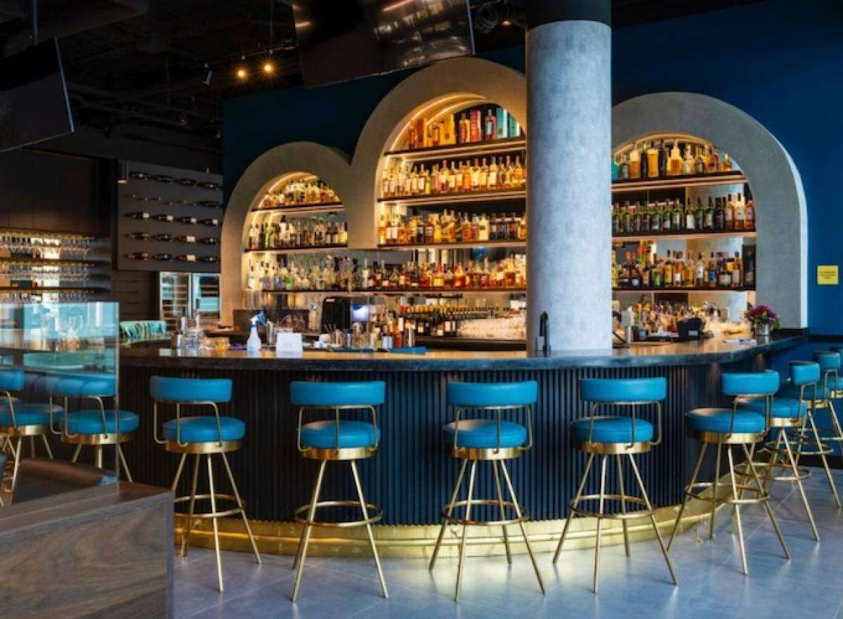 The inside of a teal and god-hued art deco-style bar