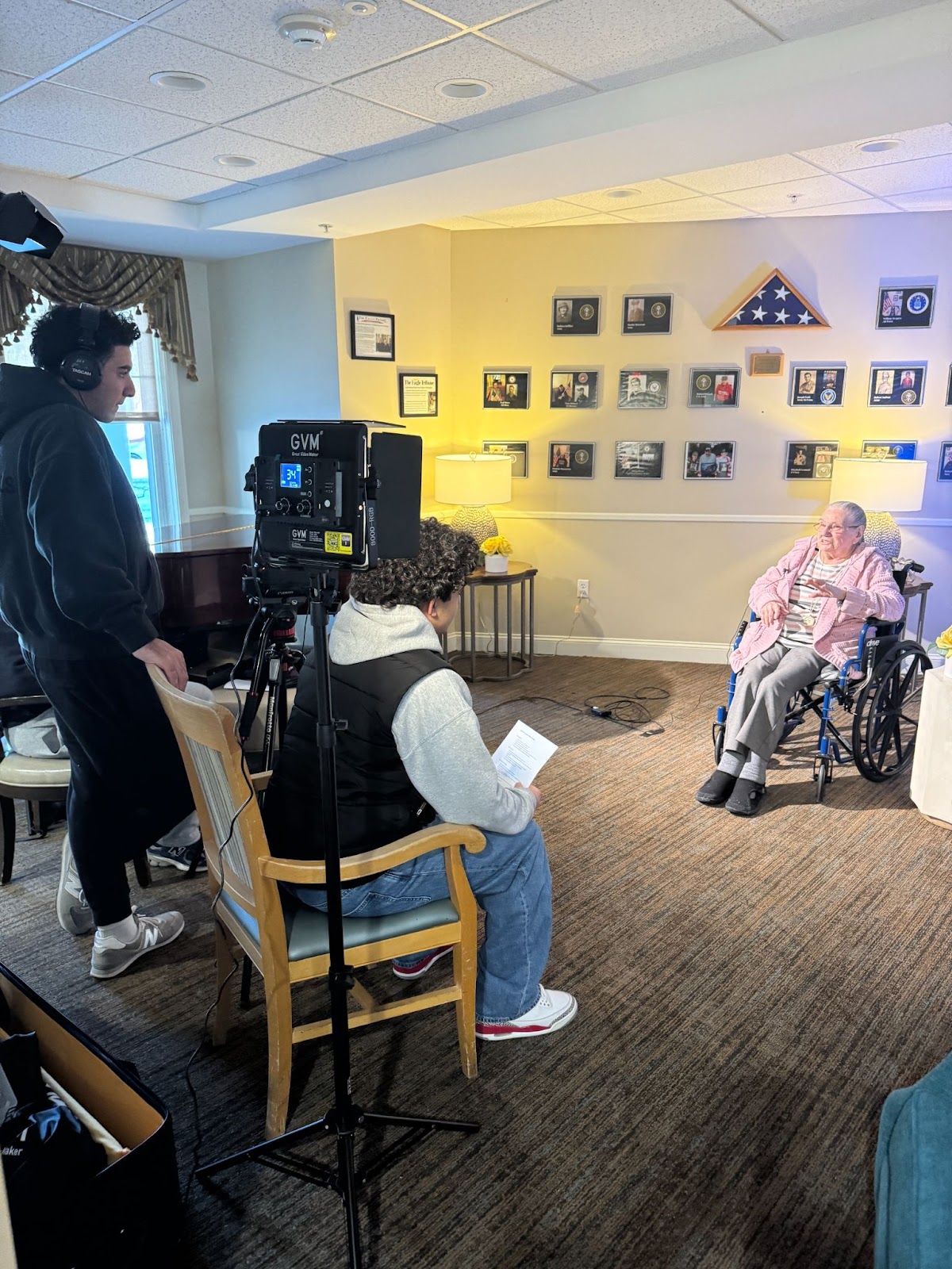 Two students interview a woman on camera