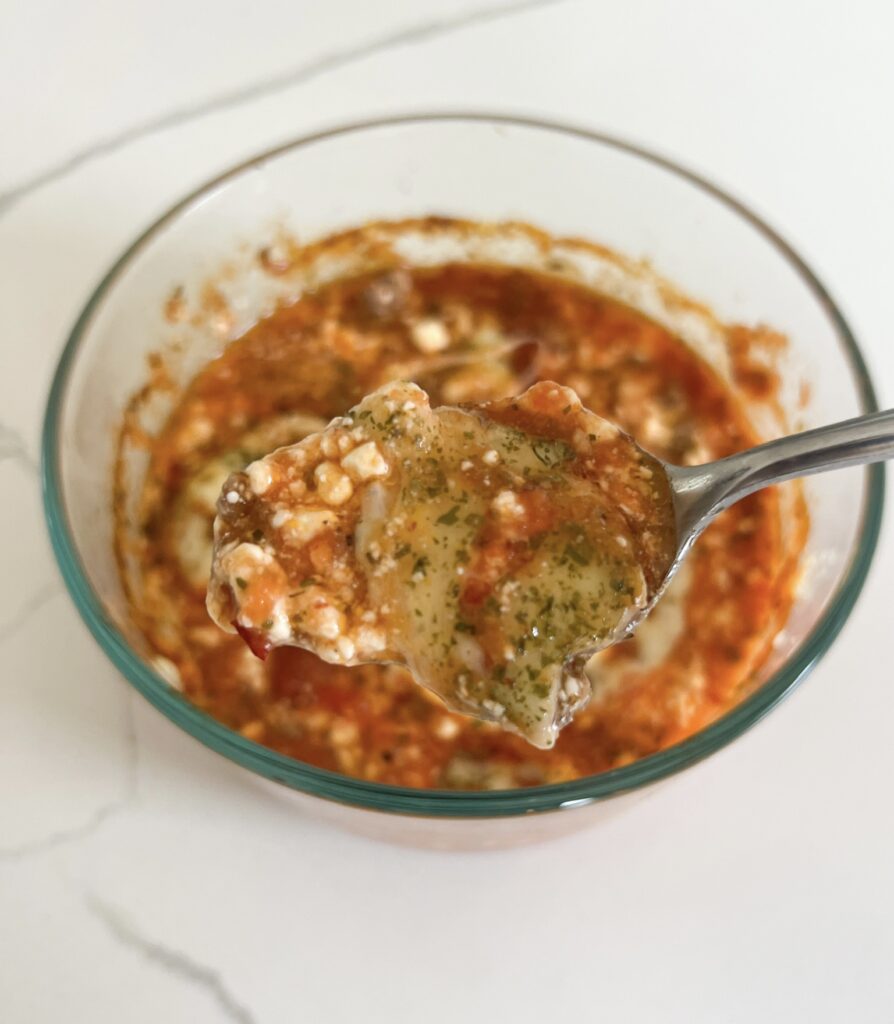 This healthy cottage cheese lasagna bowl is gluten free, high protein, low carb, keto, and single-serve. In a large glass bowl is the lasagna after baking - red marinara sauce bubbly, cottage cheese texture, herbs, melted cheese, and ground beef poking through. It looks like a classic lasagna but in the bowl. 