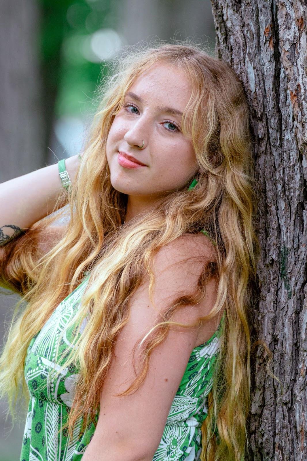 Headshot of Louise. She leans against a tree and looks at the camera.