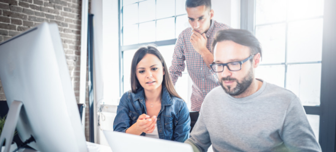 two guys and one girl looking a computer screen for data warehouse