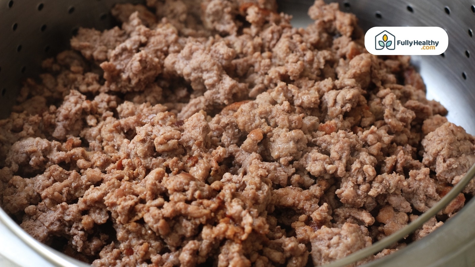 Drained cooked ground beef resting in a metal colander